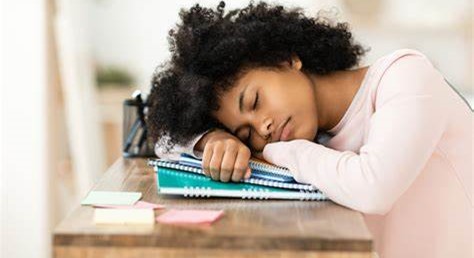 teen girl sleeping with her head resting on top of school books.